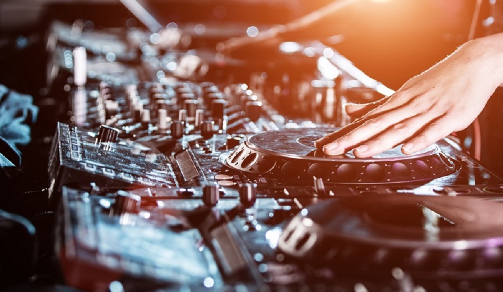 Dj mixes the track in the nightclub at party, close-up.