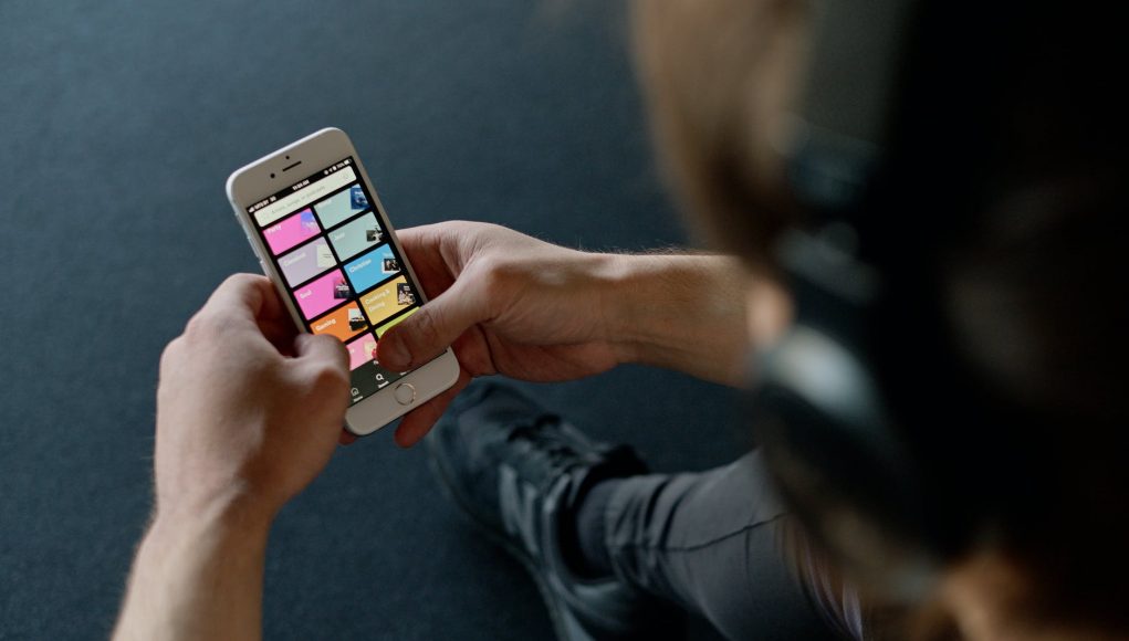 person with headphones holding a smartphone