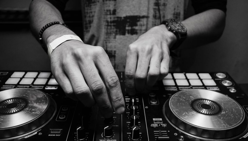 grayscale photography of person using dj controller