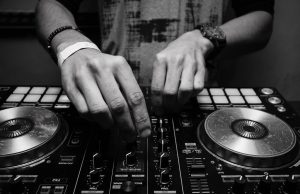grayscale photography of person using dj controller