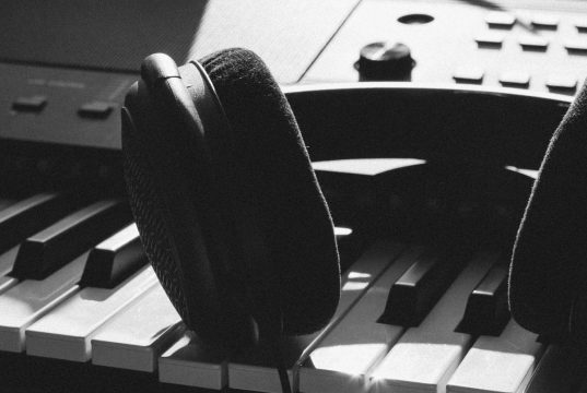 Pawas & Unnayanaa – OMM EP black wireless headphones on gray electronic keyboard