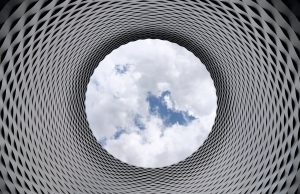 low angle photography of grey and black tunnel overlooking white cloudy and blue sky