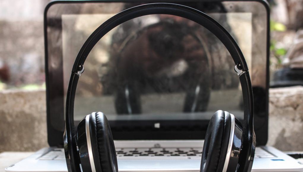 photo of black wireless headphones in front of the laptop