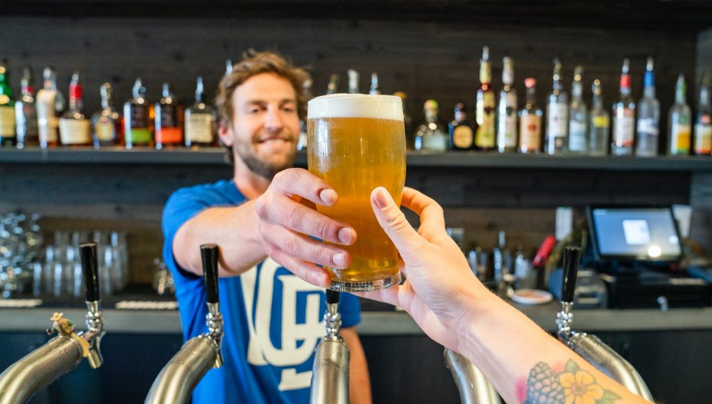 man handing a person a glass of beer
