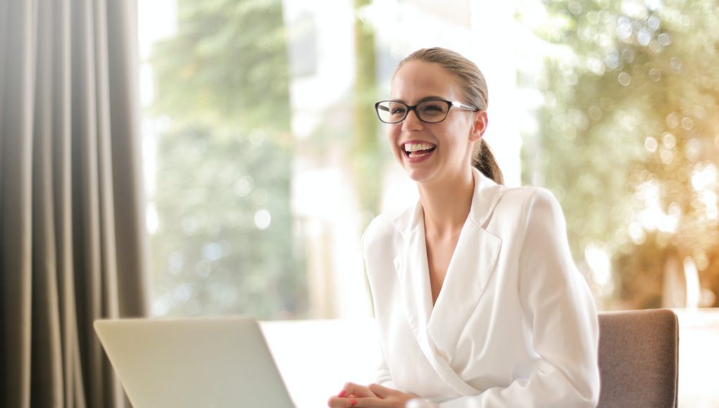 laughing businesswoman working in office with laptop