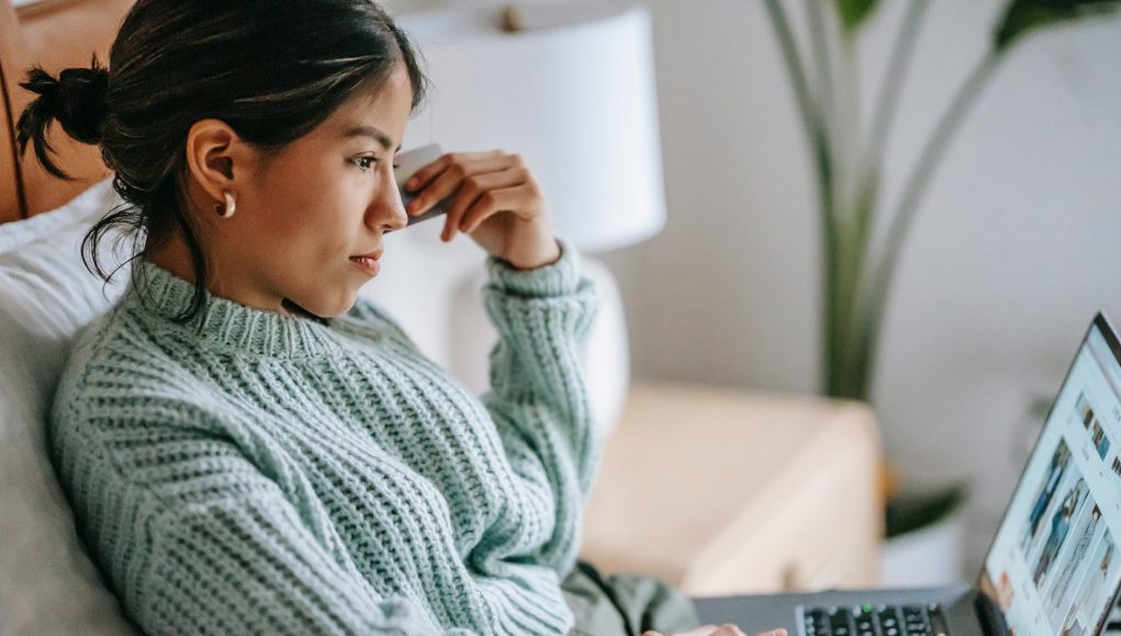 focused young ethnic woman with credit card and laptop