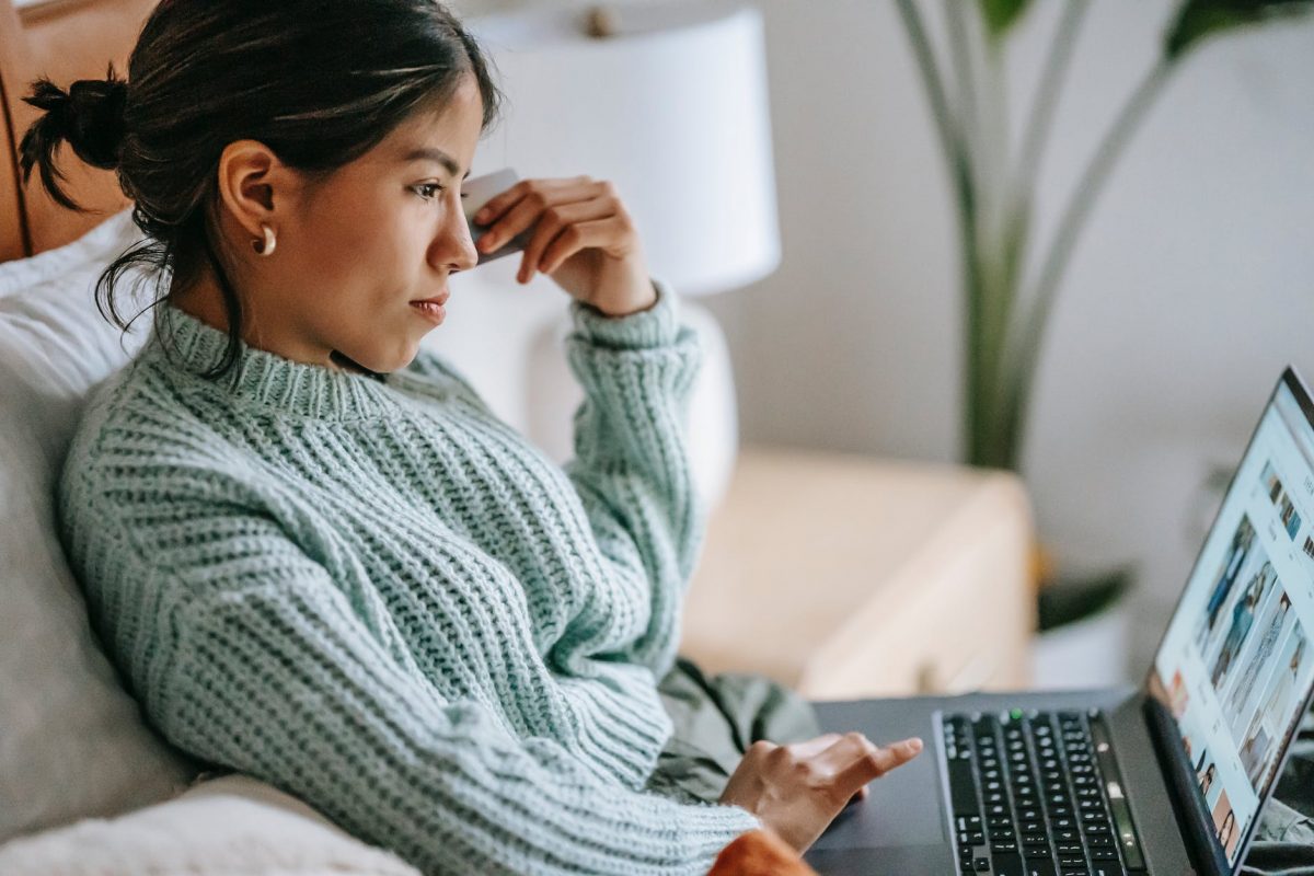 focused young ethnic woman with credit card and laptop