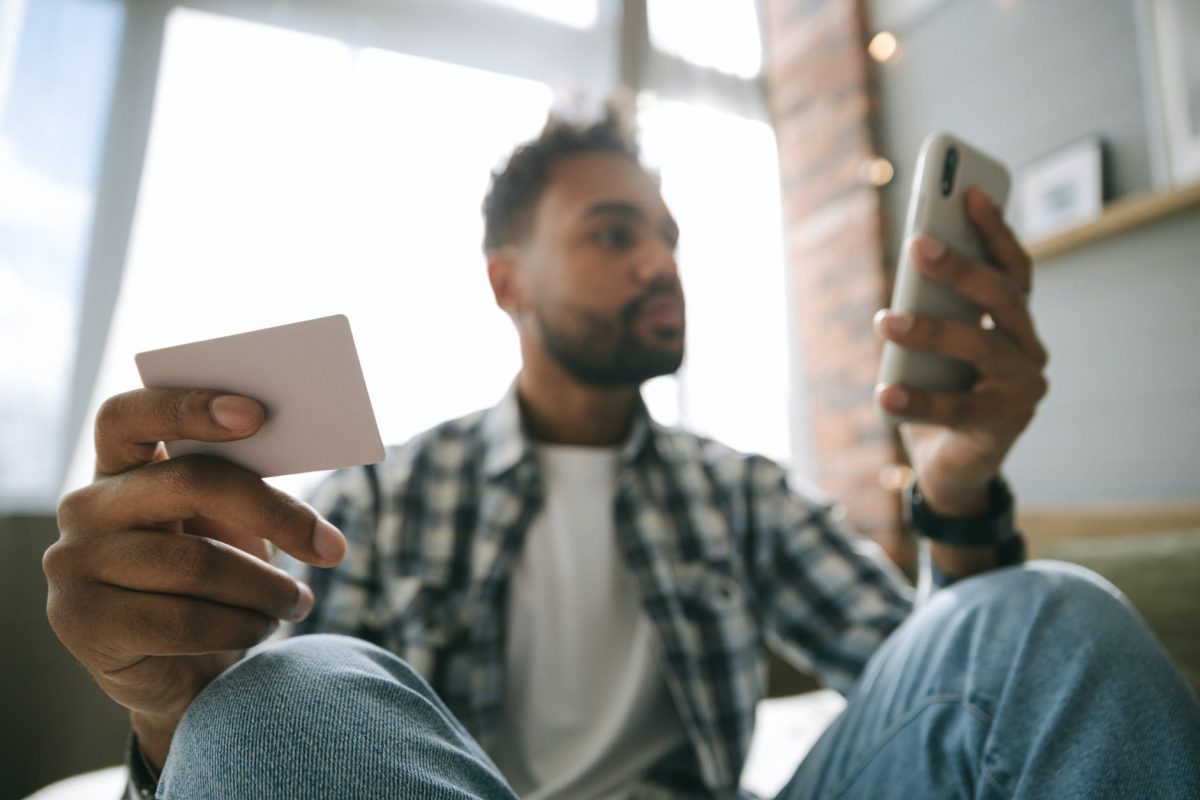 close up photo of a man holding cellphone and a card